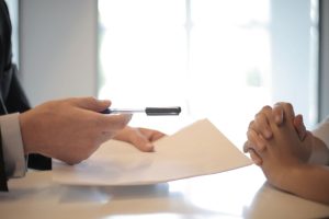 A man handing his potential renter a contract to sign and a pen